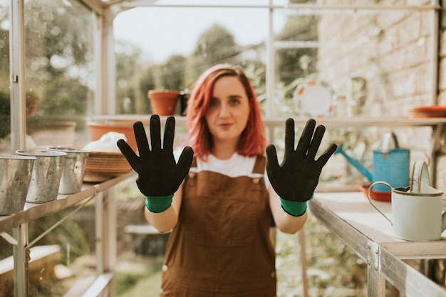 Jardinier de femme avec des gants noirs en serre chaude