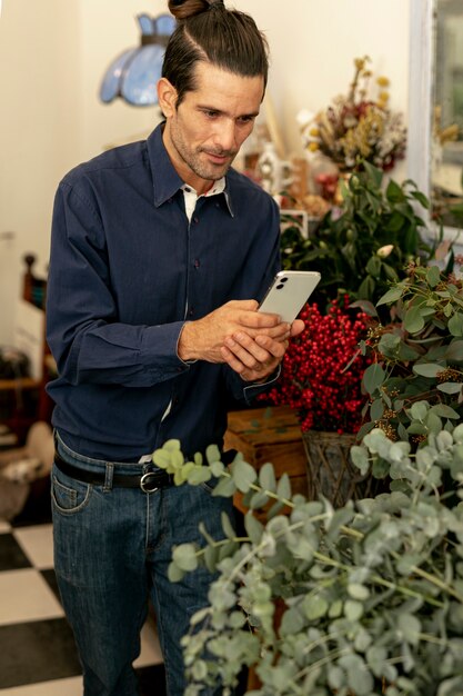 Jardinier homme aux cheveux longs photographiant les plantes