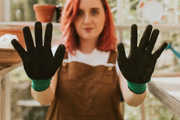 Photo gratuite jardinier de jeune femme avec des gants noirs dans une petite ferme biologique