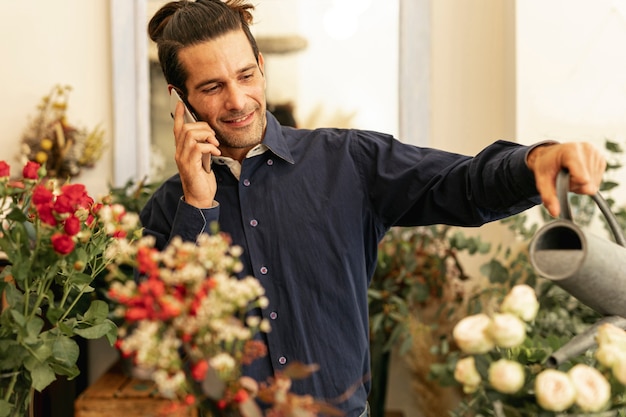 Photo gratuite jardinier, parler au téléphone et arroser les plantes