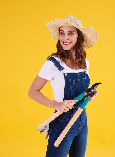 Jardinier souriant tenant des taille-haies dans le studio tourné