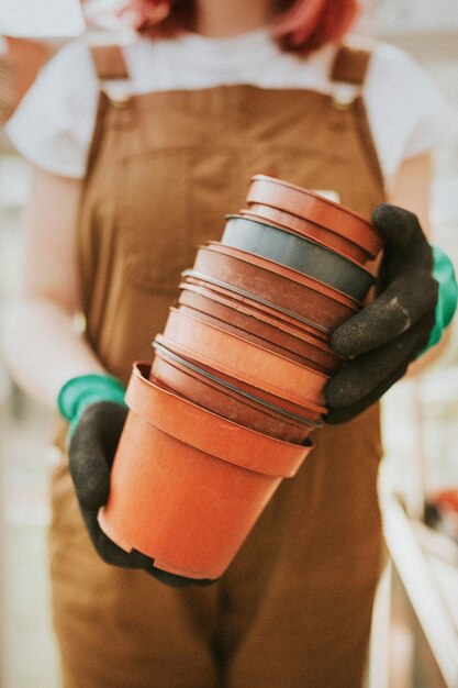 Jardinier tenant des pots de fleurs vides