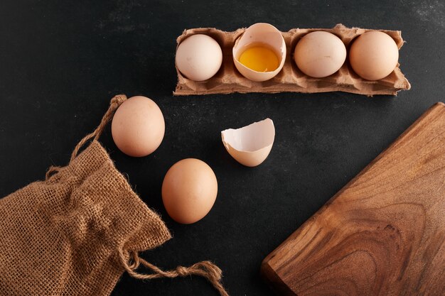 Jaune d'oeuf à l'intérieur de la coquille d'oeuf sur fond noir dans le plateau en carton.