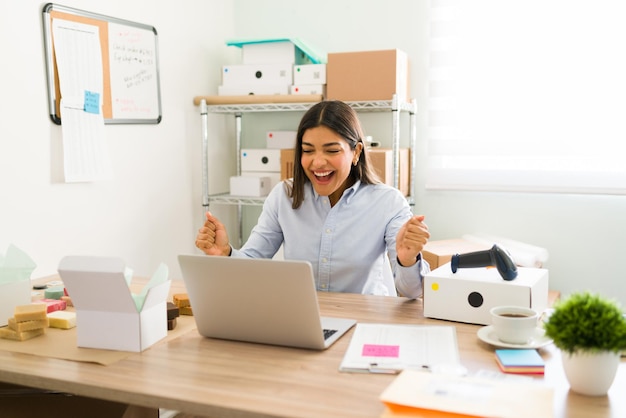 Je ne peux pas le croire. Une femme entrepreneur excitée qui a l'air surprise et crie de bonheur parce que tous les clients en ligne commandent