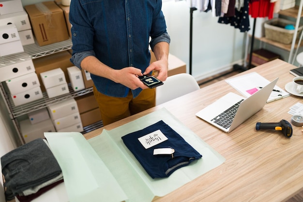 Photo gratuite je poste cette photo sur les réseaux sociaux de l'entreprise. jeune homme prenant une photo d'une note de remerciement sur le colis d'un client