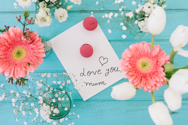 Photo gratuite je t'aime inscription maman avec des fleurs et des macarons