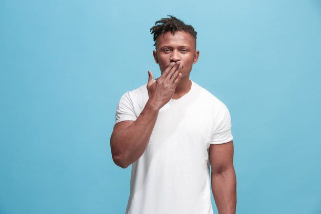 Je t'embrasse. Portrait d'un homme afro attrayant avec un baiser d'air sur les lèvres. Studio bleu. Beau portrait masculin. Jeune homme drôle émotionnel heureux. Concept d'émotions faciales humaines. Couleurs tendance