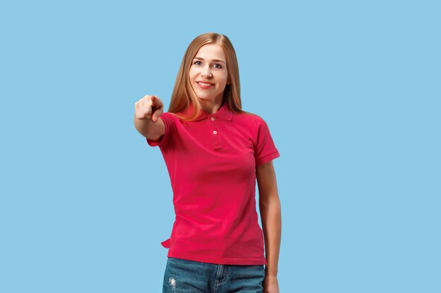 Je te choisis et commande. La femme d'affaires souriante vous pointer, vous voulez, portrait gros plan demi-longueur sur studio bleu