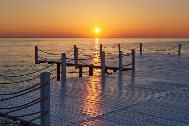 Jetée en bois sur un coucher de soleil orange fantaisie.