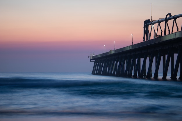 Jetée près de la mer calme sous le beau ciel coucher de soleil