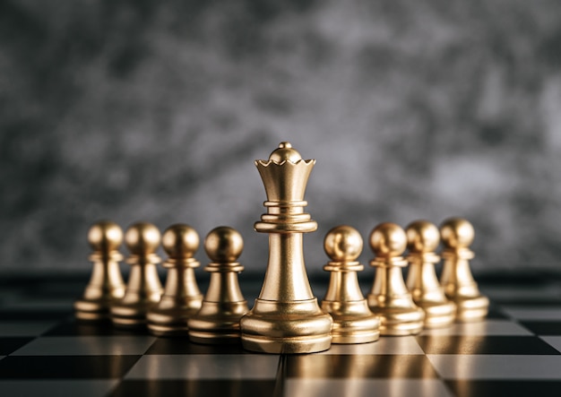 Jeu d'échecs d'or sur un jeu d'échiquier pour le concept de leadership métaphorique d'affaires