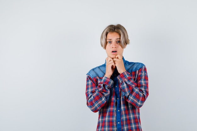 Photo gratuite jeune adolescent en chemise à carreaux avec les mains sur le menton et à l'air agité