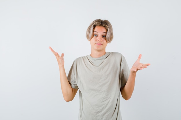 Jeune Adolescent Montrant Un Geste Impuissant En T-shirt Et L'air Perplexe. Vue De Face.