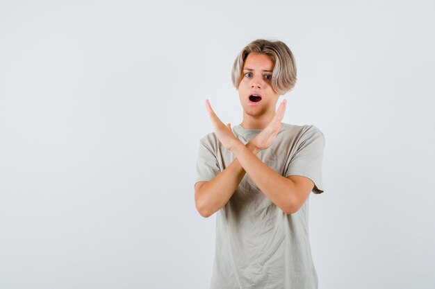 Jeune adolescent montrant un geste de refus en t-shirt et l'air ennuyé. vue de face.