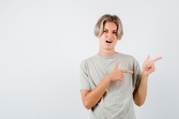 Jeune adolescent pointant vers la droite en t-shirt et ayant l'air mécontent. vue de face.