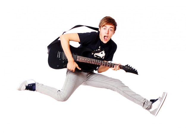Jeune adolescent sautant avec guitare