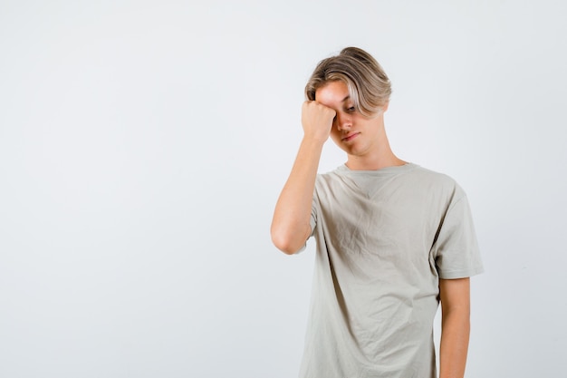 Jeune adolescent se sentant mal à la tête en t-shirt et ayant l'air contrarié. vue de face.