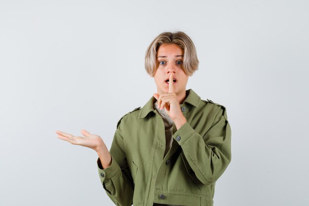 Jeune adolescent en t-shirt affichant et faisant un geste de silence