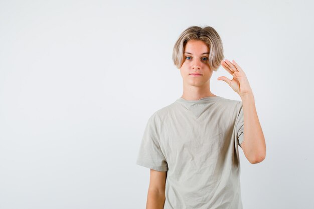 Jeune adolescent en t-shirt montrant un geste bla-bla-bla et semblant sarcastique, vue de face.