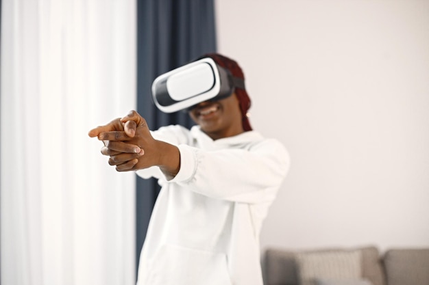 Jeune adolescente debout dans le salon portant des lunettes de réalité virtuelle