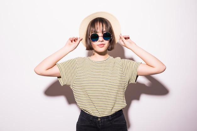 Jeune adolescente hipster attrayante à la mode en lunettes de soleil et chapeau de paille isolé