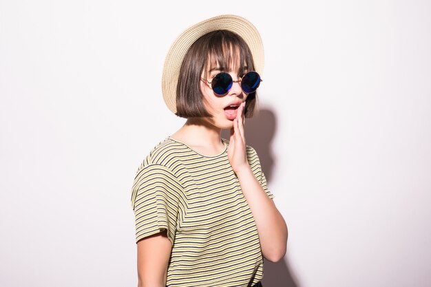Jeune adolescente hipster attrayante à la mode en lunettes de soleil et chapeau de paille isolé