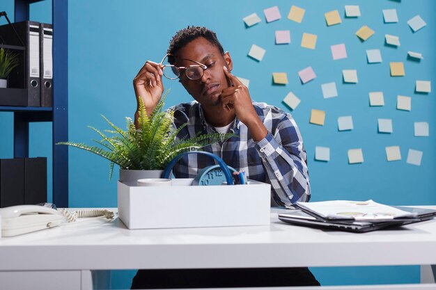 Jeune adulte afro-américain au chômage en raison de l'échec du plan de redressement financier de l'entreprise. Employé de bureau déprimé et bouleversé rassemblant des effets personnels en raison d'un licenciement.