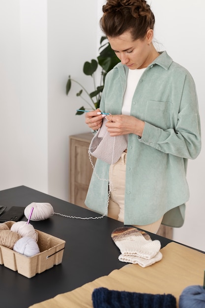 Photo gratuite jeune adulte organisant ses produits de tricot