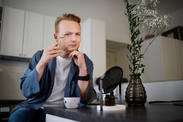 Photo gratuite jeune adulte utilisant un produit de soin du visage