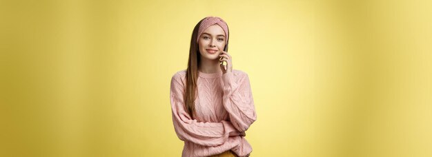 Une jeune amie élégante qui a une conversation agréable par téléphone en tenant un smartphone près de l'oreille.