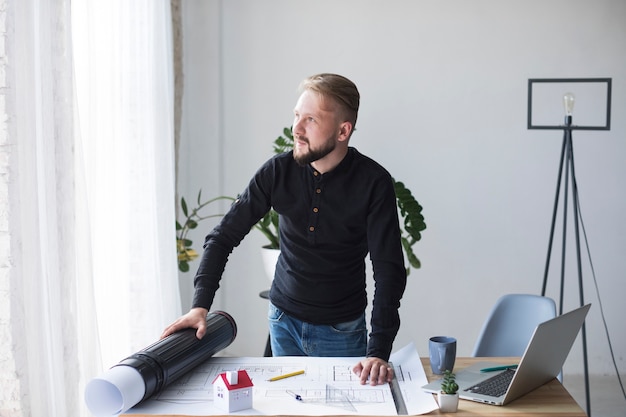 Un jeune architecte de sexe masculin dans son bureau à la recherche de suite