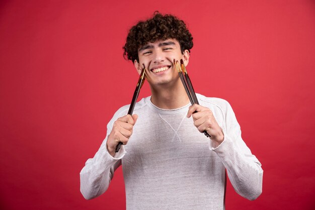 Jeune artiste avec des pinceaux se sentant gai.