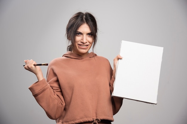 Jeune artiste posant avec des pinceaux et de la toile