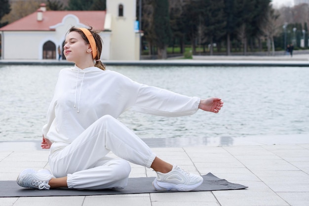 Jeune athlète assise sur un tapis et étirant son corps Photo de haute qualité