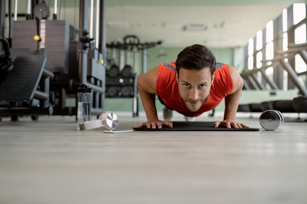 Jeune athlète faisant des pompes tout en faisant de l'exercice dans une salle de sport