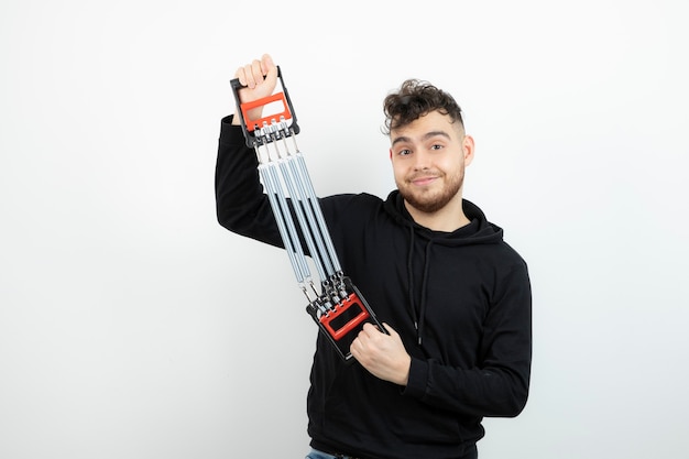 Jeune athlète masculin tenant l'outil de gym exercice sur mur blanc.