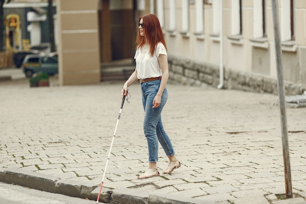 Jeune aveugle avec une longue canne marchant dans une ville