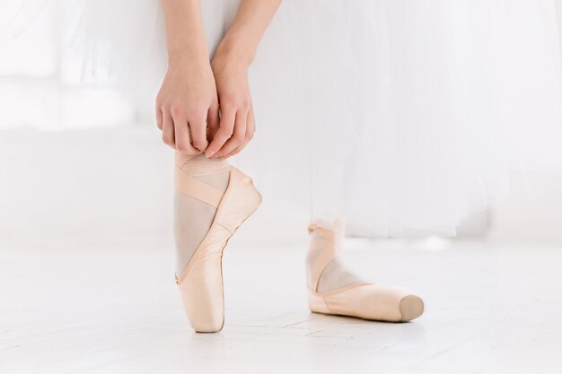 Jeune ballerine dansant, gros plan sur les jambes et les chaussures, debout en position de pointe.