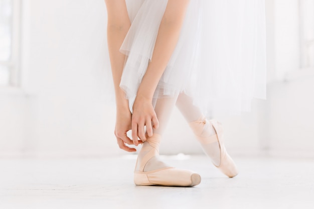 Jeune ballerine dansant, gros plan sur les jambes et les chaussures, debout en position de pointe.