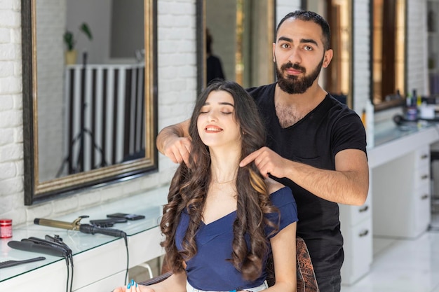 Photo gratuite jeune barbier montrant les cheveux ondulés de la fille à la caméra photo de haute qualité