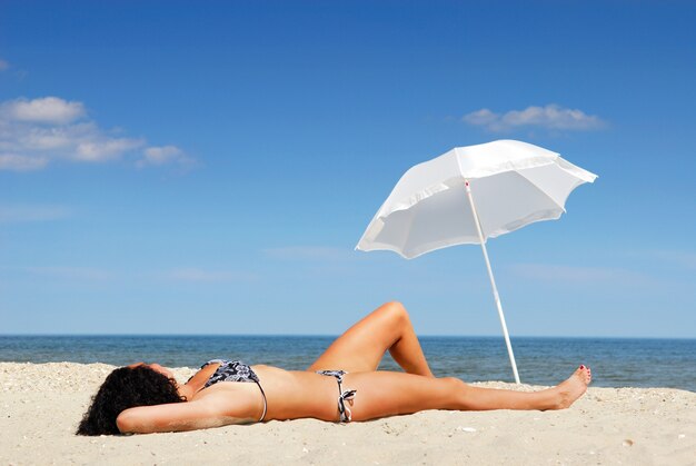 Jeune beau corps féminin allongé sur la plage