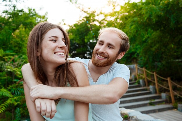 Jeune beau couple embrassant, souriant, marchant dans le mur extérieur du parc.