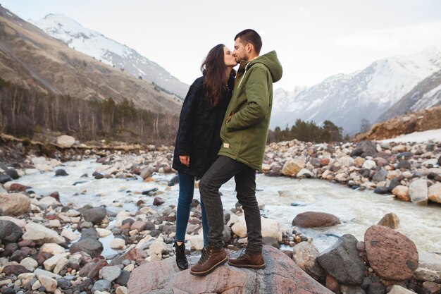 Jeune beau couple hipster amoureux, marchant au bord de la rivière, nature sauvage, vacances d'hiver