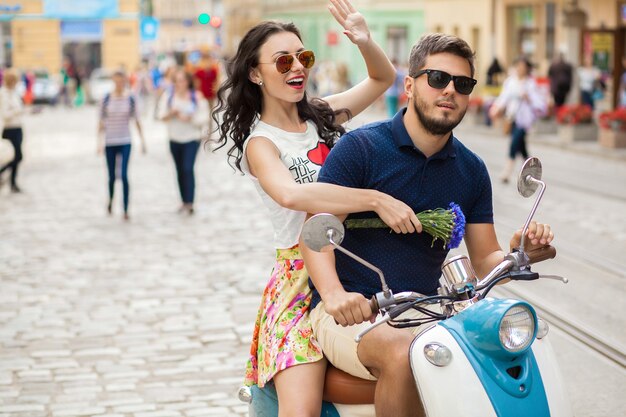 Jeune beau couple hipster à cheval sur la rue de la ville de moto