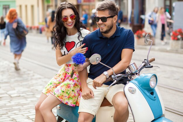 Jeune beau couple hipster à cheval sur la rue de la ville de moto