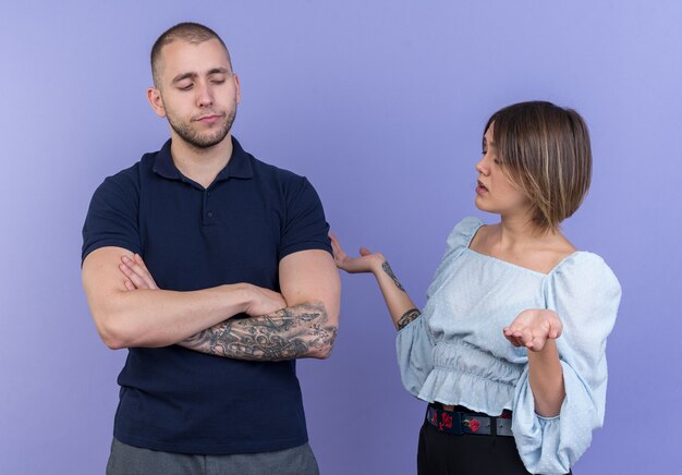 Jeune beau couple homme et femme se disputant une femme mécontente regardant son petit ami offensé avec les bras croisés debout