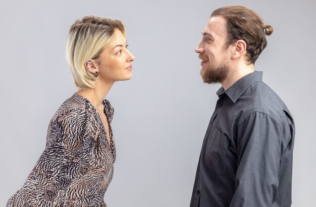 Jeune beau couple homme et femme se regardant en souriant joyeusement célébrant la Saint-Valentin debout sur un mur blanc