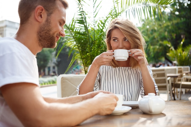 Jeune beau couple parlant, souriant, se reposant au café.