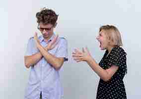 Photo gratuite jeune beau couple se quereller femme criant sur son petit ami qui montrant le geste d'arrêt avec hfrowning face au mur blanc