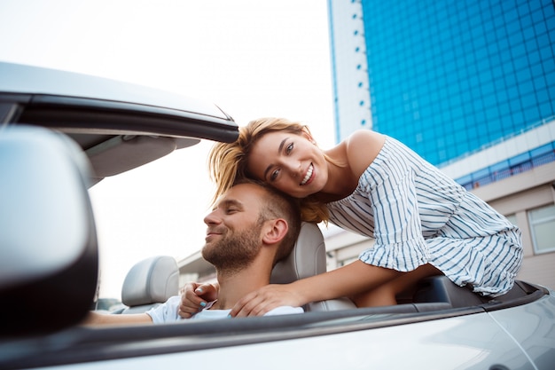 Jeune beau couple souriant, assis dans la voiture près de la mer.